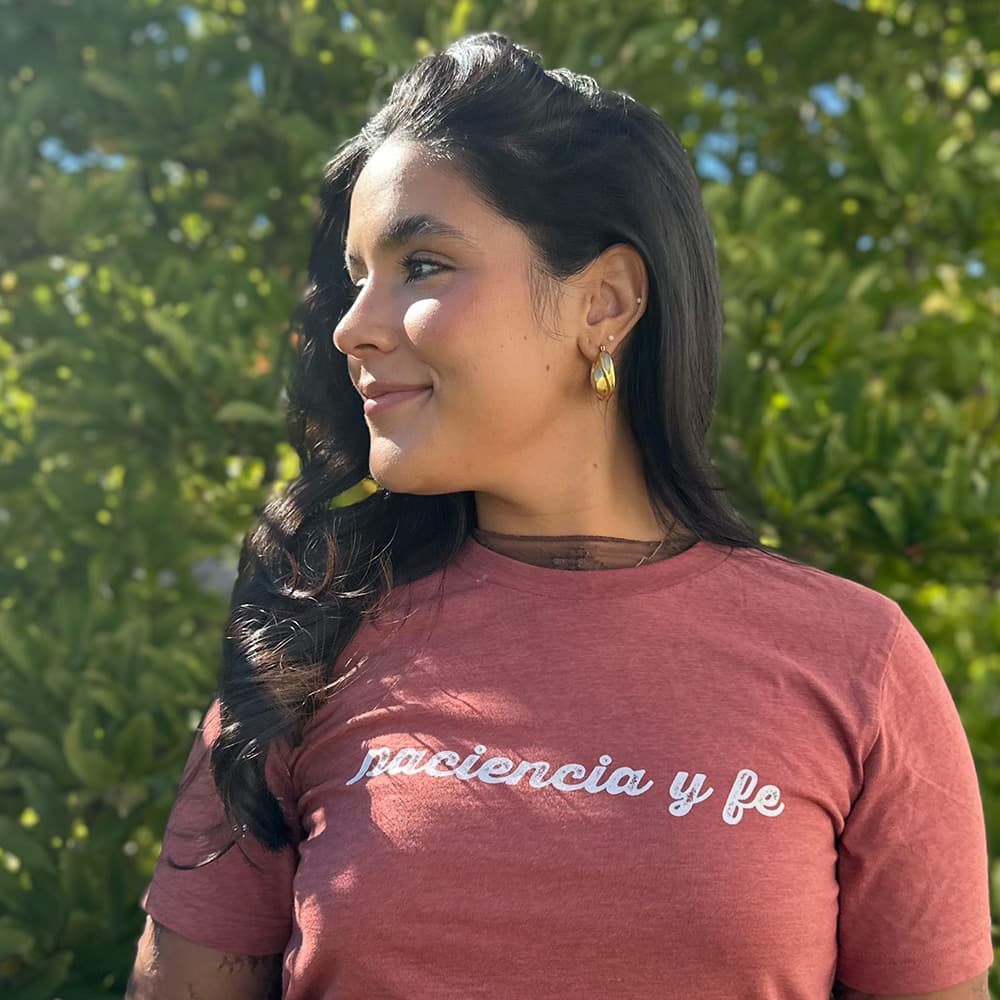 Heather mauve crew-neck t-shirt with white script text reading "paciencia y fe."