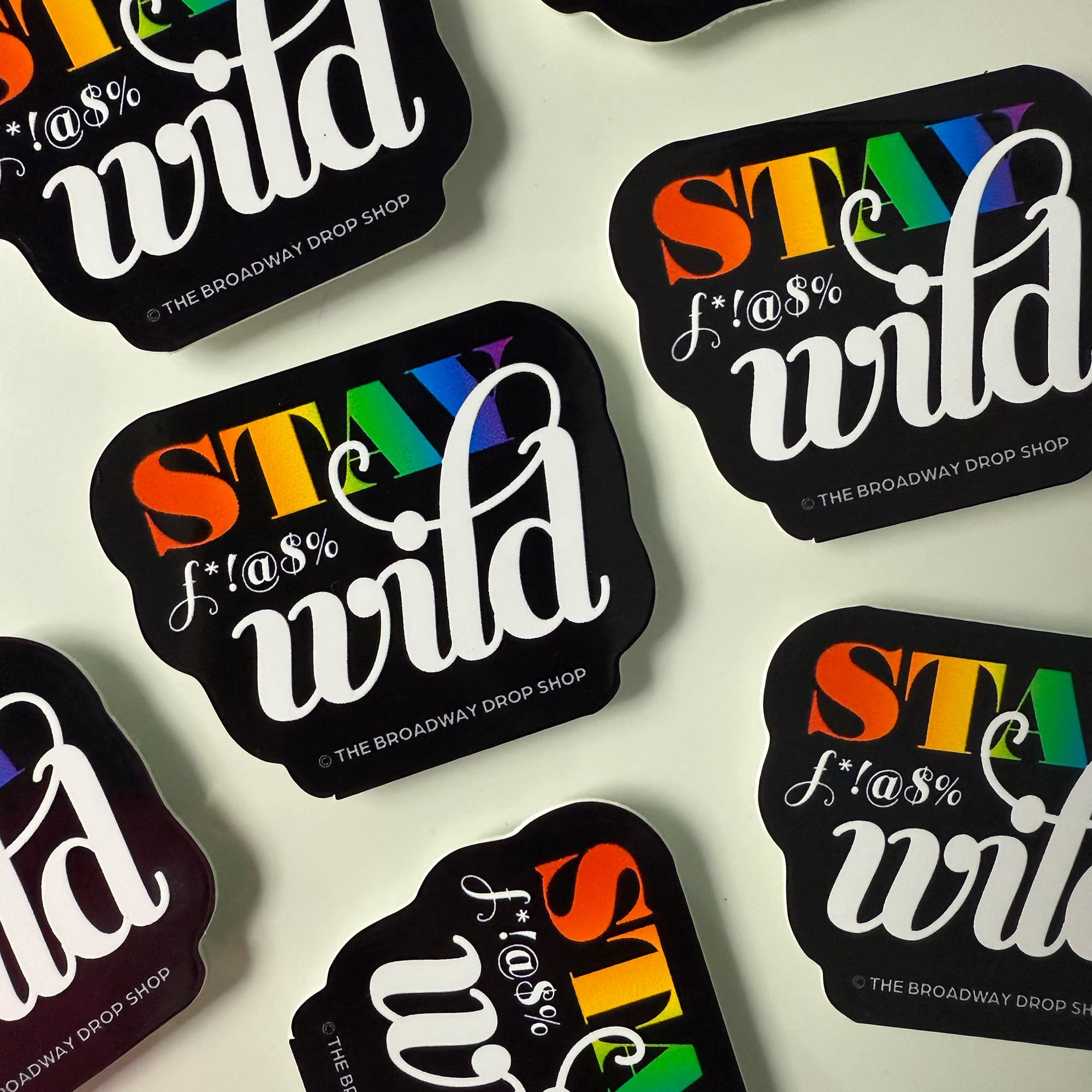 A rainbow colored sticker that says Stay F**'in Wild