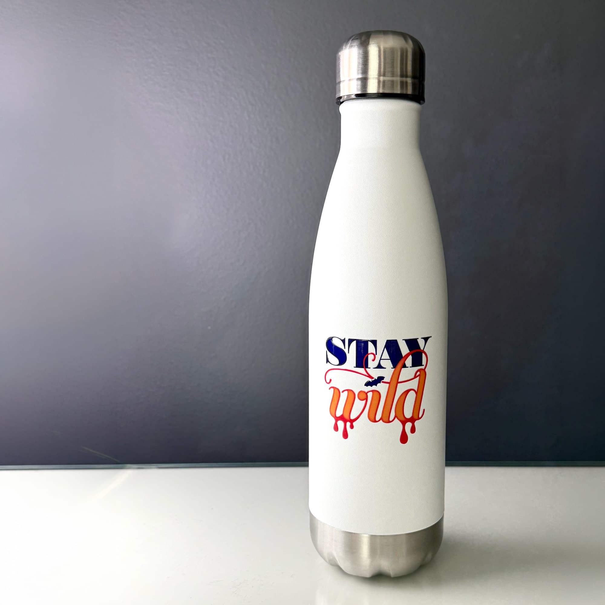 The words "stay wild" with a teeny tiny bat printed on a white water bottle